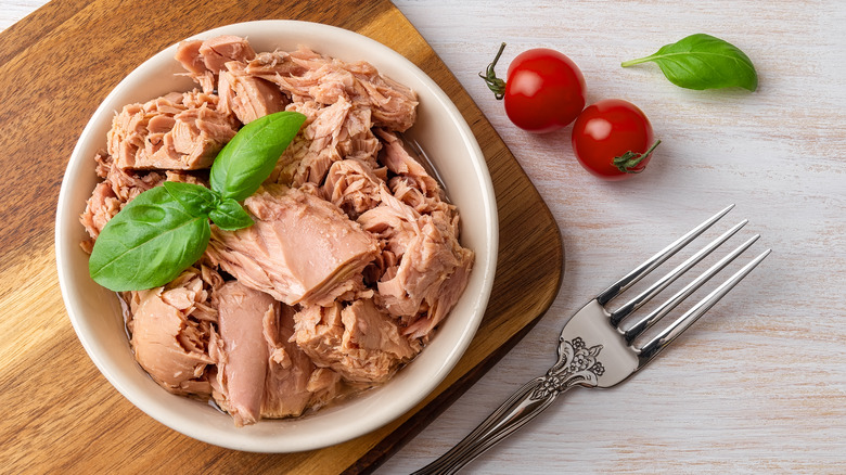 Bowl of tuna on cutting board with tomatoes