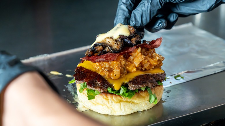 chef adding toppings to burger