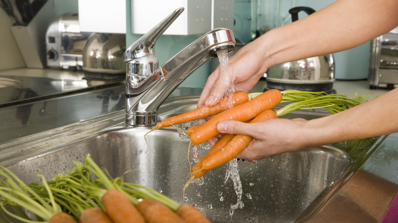 hands washing carrots in sink