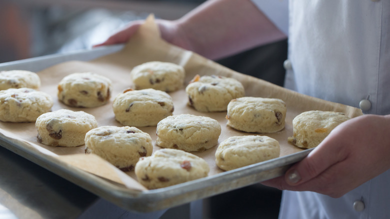 person holding baking tray of scones