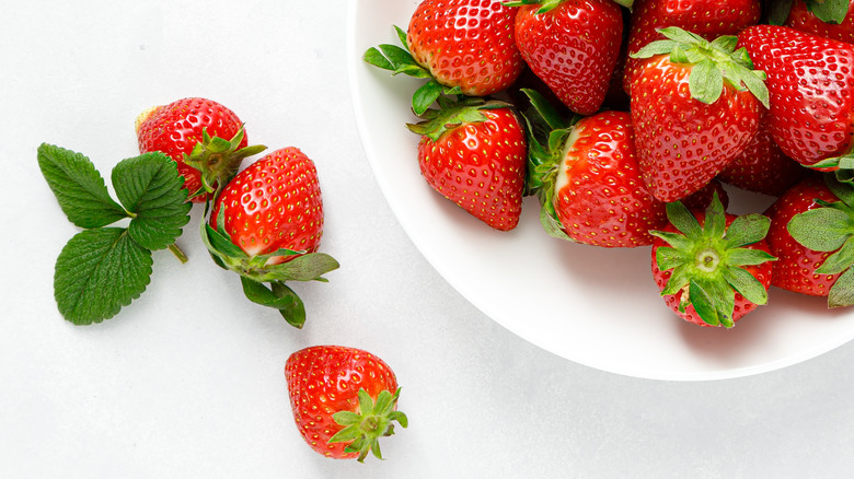 strawberries in and around white bowl