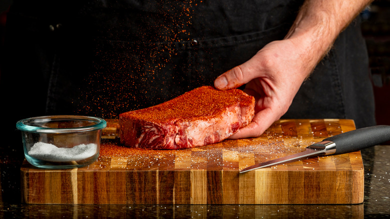 person seasoning strip steak