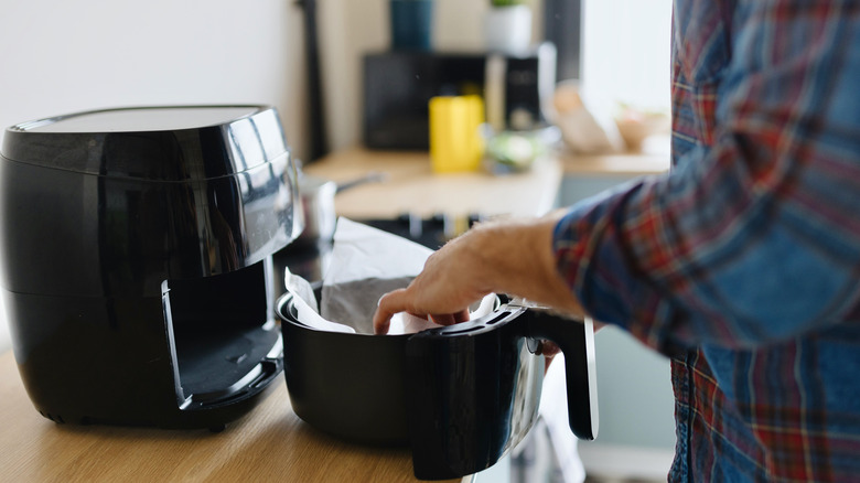 man placing paper in air fryer