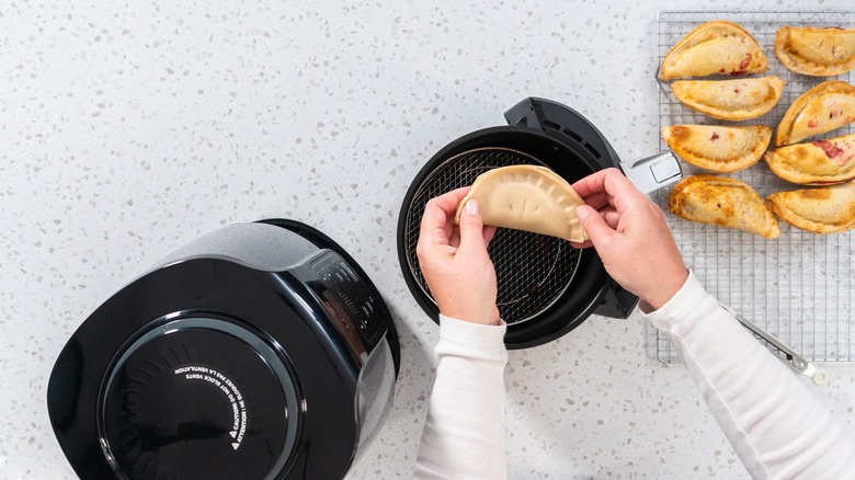 Person putting empanadas in air fryer