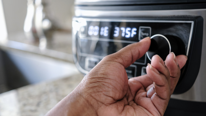 hand adjusting air fryer dial