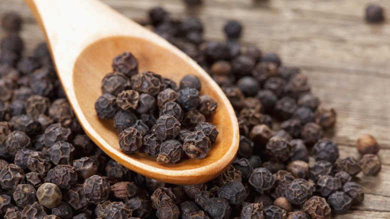 black peppercorns in wooden spoon