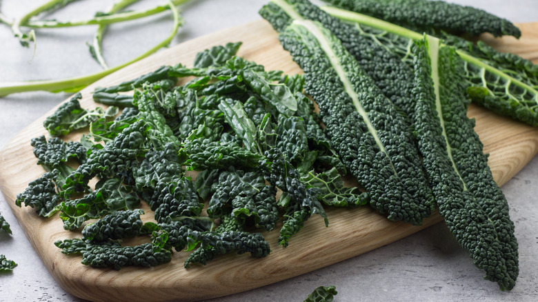 A board with raw torn and whole kale