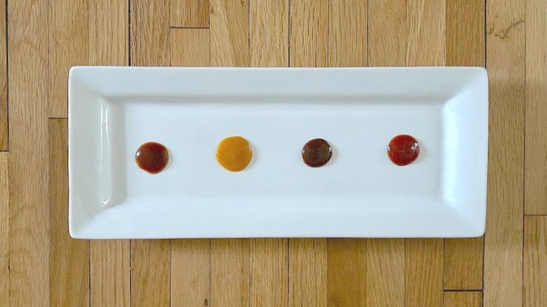 Rectangular white plate with four pools of different colored BBQ sauce on it