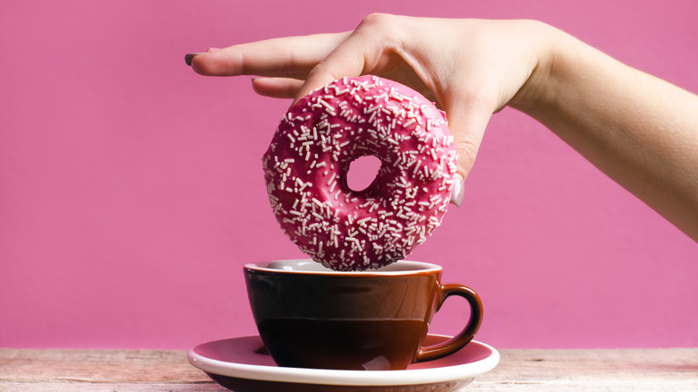 hand dunking donut in coffee