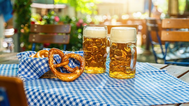 Two glasses of beer with a pretzel 