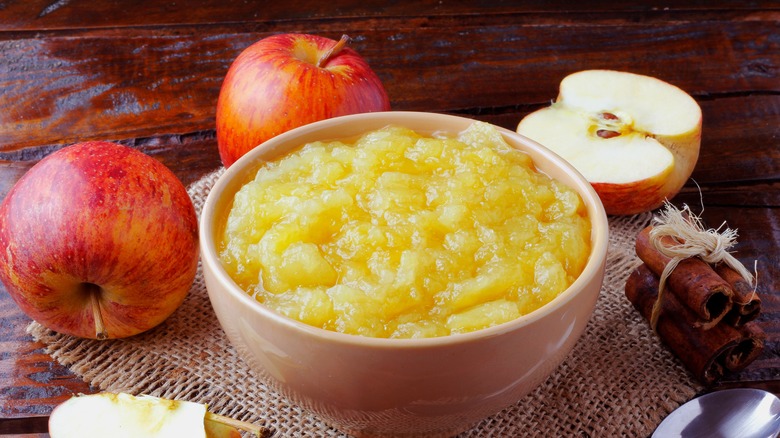 Bowl of applesauce alongside whole apples