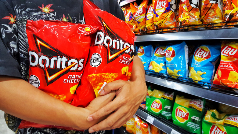 person holding doritos nacho cheese bags in store