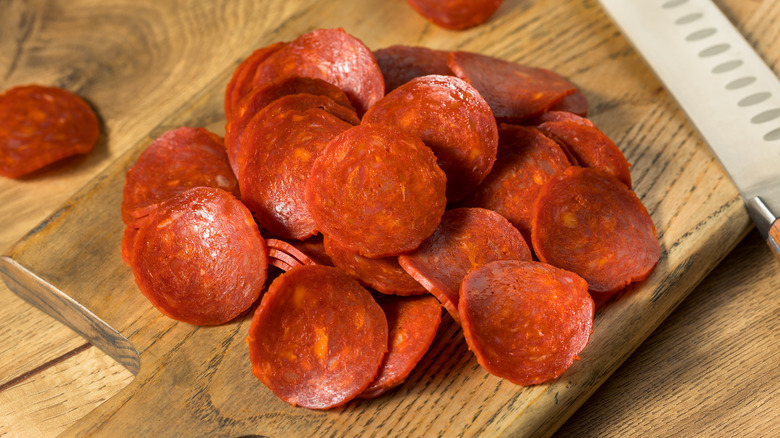 Sliced pepperoni on wooden board