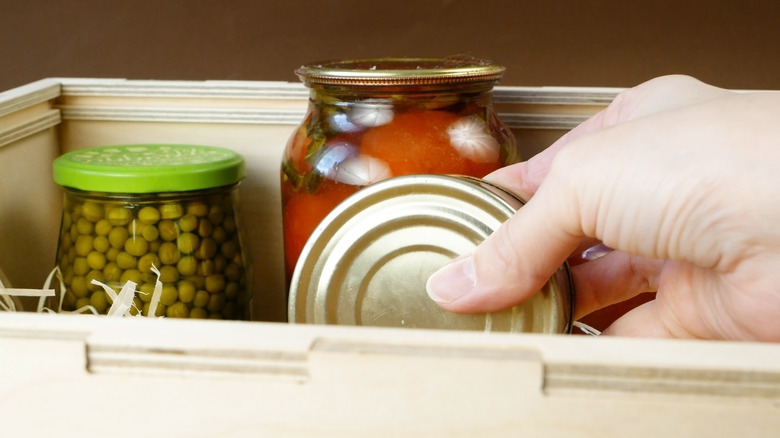 hand holding canned food with jars