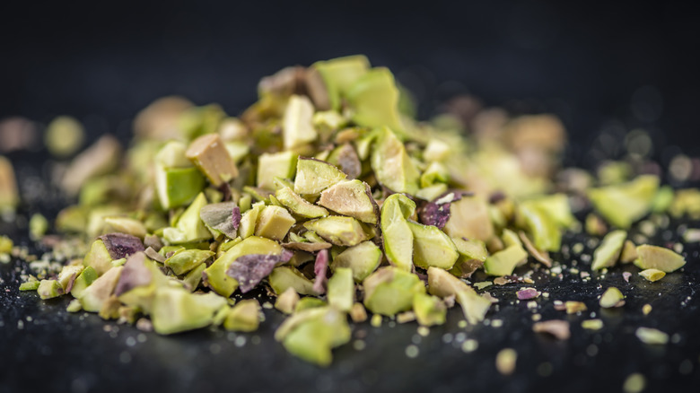 roasted and chopped pistachios on dark background