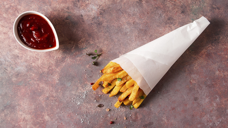 A bag of french fries next to a dipping sauce