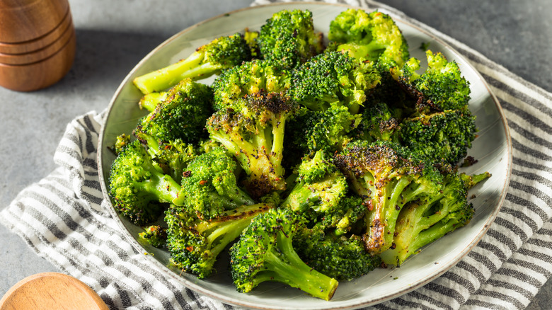 Roasted broccoli in a bowl with pepper grinder