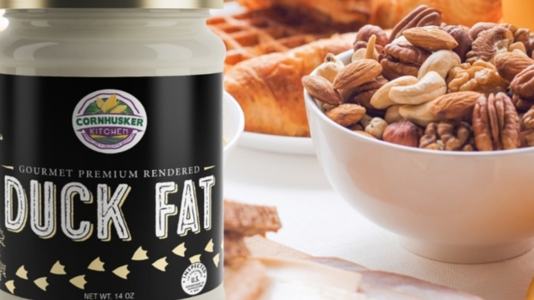Jar of duck fat sits next to a bowl of nuts