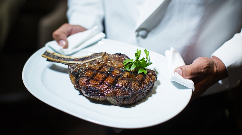 Server holding steak on plate