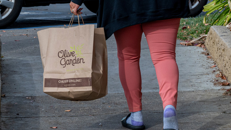 Customer carries to-go bag of olive garden food