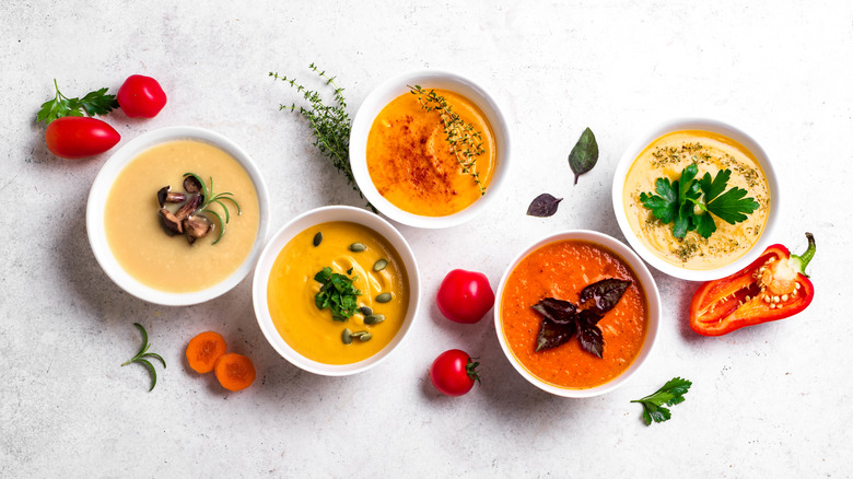 a line of five different kinds of soup in bowls