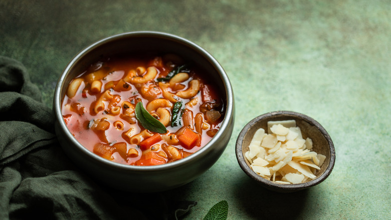 a bowl of minestrone next to a bowl of cheese flakes