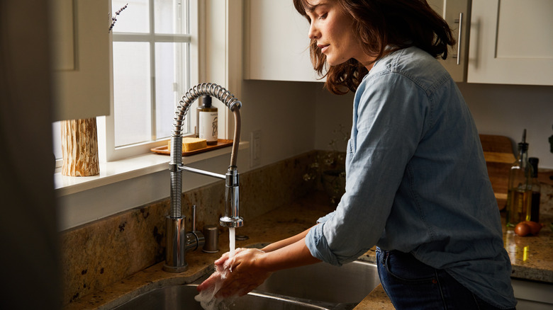 woman using a tall sprayer hose faucet