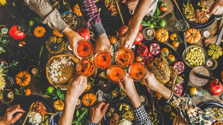 Hands holding glasses together over meal