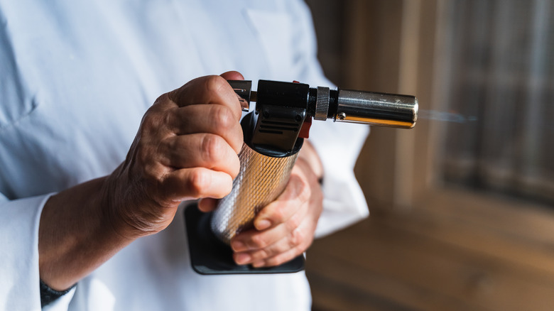 Person using small kitchen torch