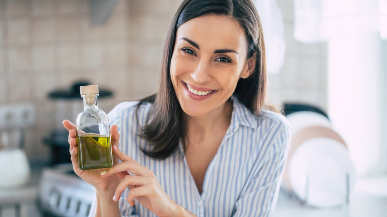 woman smiling with oil bottle