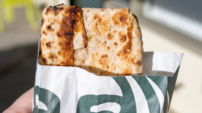 Person holding a spinach feta wrap from Starbucks.