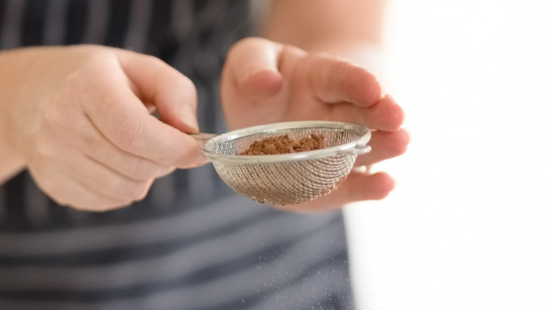 Using a sieve to sift cocoa powder