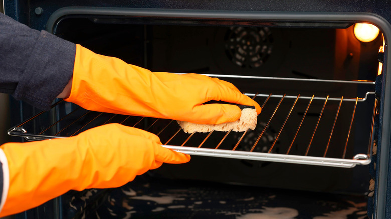 Gloved hands cleaning oven racks