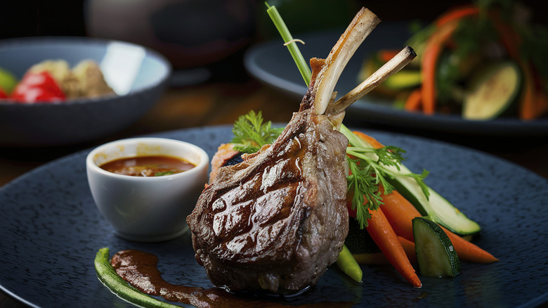 A thick bone-in lamb chop on the table at a fancy steakhouse