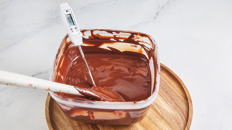 Glass bowl with melted chocolate and thermometer