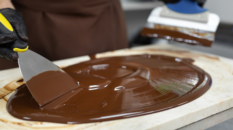 Spreading chocolate over a surface with a metal spatula.