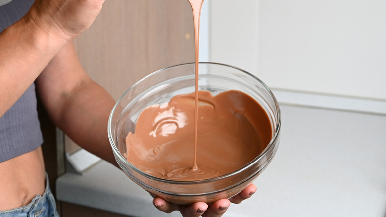 Person holding bowl of tempered chocolate