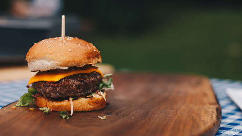 Cheeseburger with toothpick on wooden board