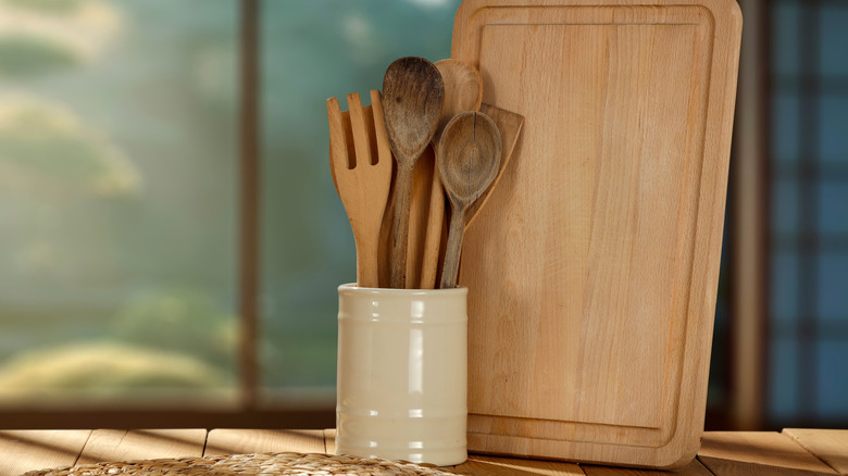 Variety of wooden utensils in a ceramic container on a kitchen counter