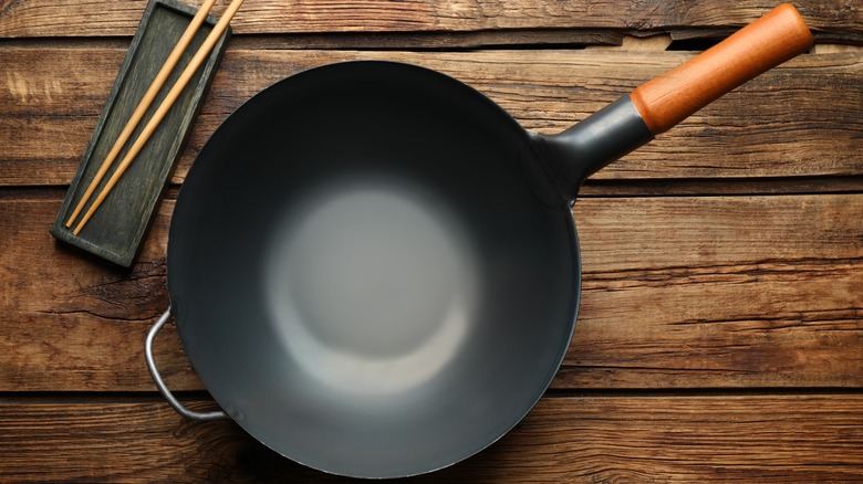 empty wok on a wooden bench next to chopsticks