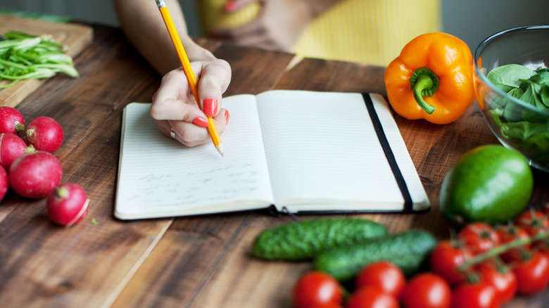 Person writing in notebook while cooking