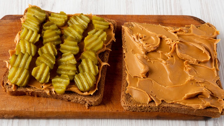 A deconstructed peanut butter and pickle sandwich on a cutting board