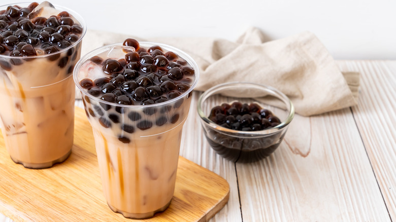 two boba teas on wood with bowl of boba