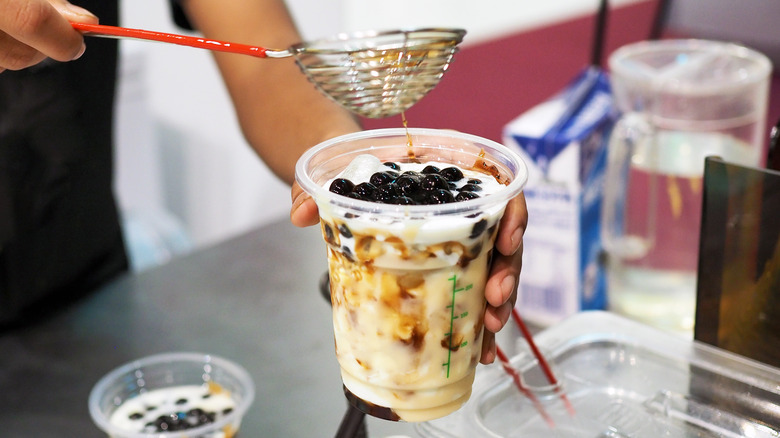 hands preparing boba tea at store