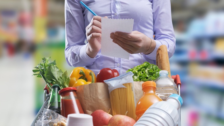 Person crossing items from her shopping list in grocery store