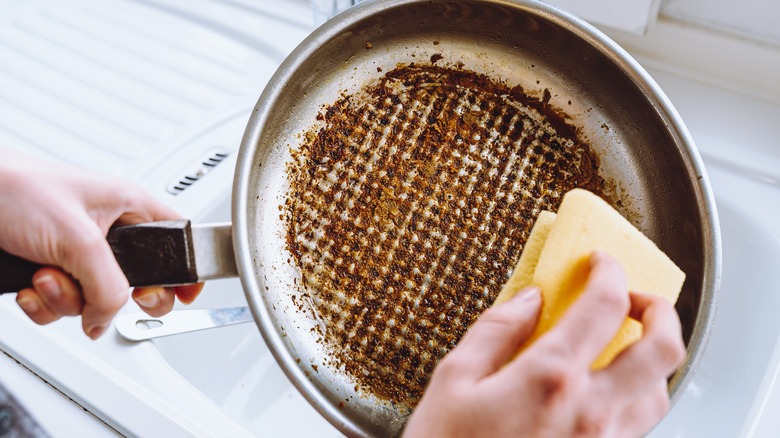 cleaning dirty pan with yellow sponge