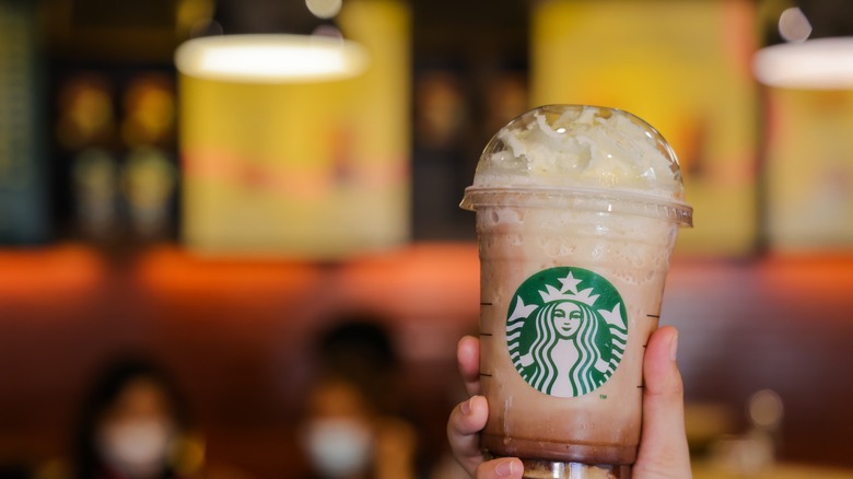 A hand holding a Starbucks iced drink