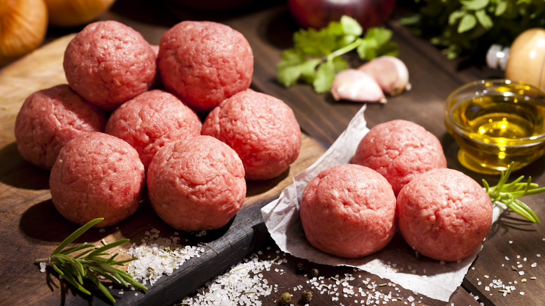 Raw meatballs on wooden cutting board