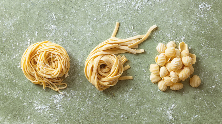 Fresh linguine nest, fresh fettuccine nest and pile of fresh shell pasta.