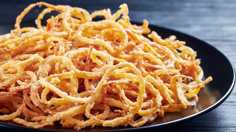 Fried onions on a black plate